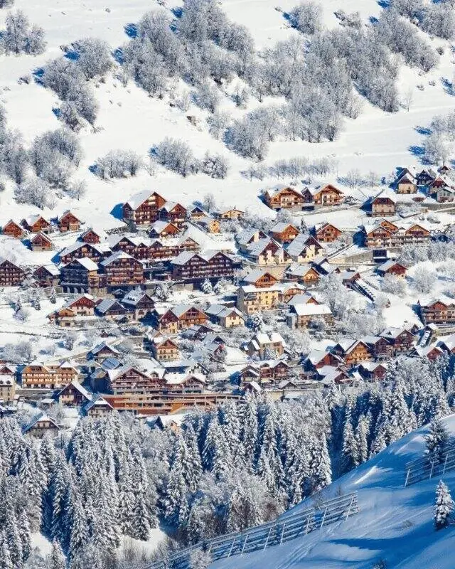 Chalets en bois enneigés parmi les arbres givrés, du côté de l’Alpe d’Huez