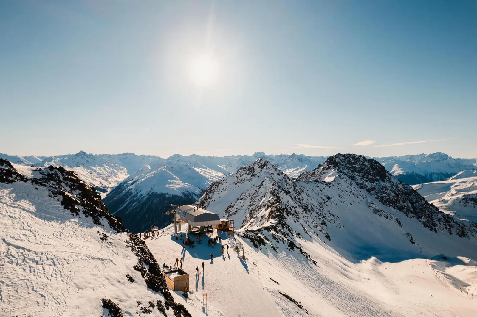 Bergstation eines Sessellifts über verschneiten Alpengipfeln in der Wintersonne