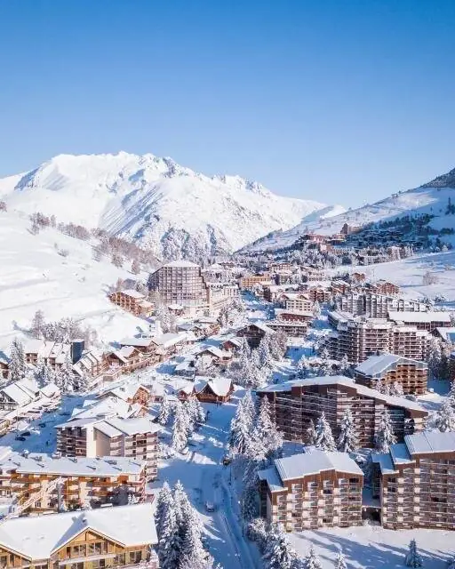 Le village et les pistes des 2 Alpes sous la neige fraîche et le ciel bleu
