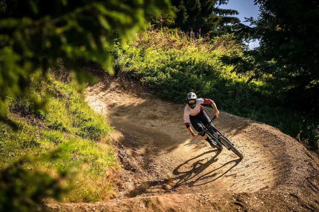 Vététiste dans un virage relevé du bike park des Gets en été, Portes du Soleil
