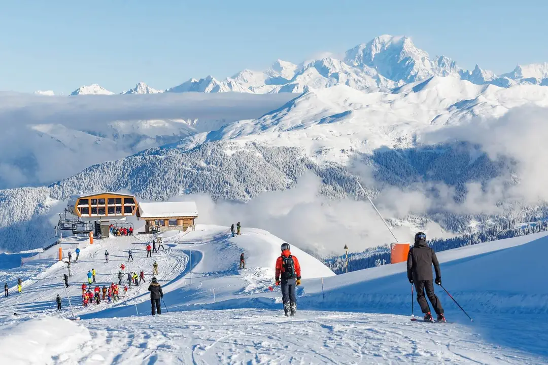 Skifahrer auf den Pisten von Méribel mit Blick auf den Mont Blanc über einem Wolkenmeer, Les 3 Vallées
