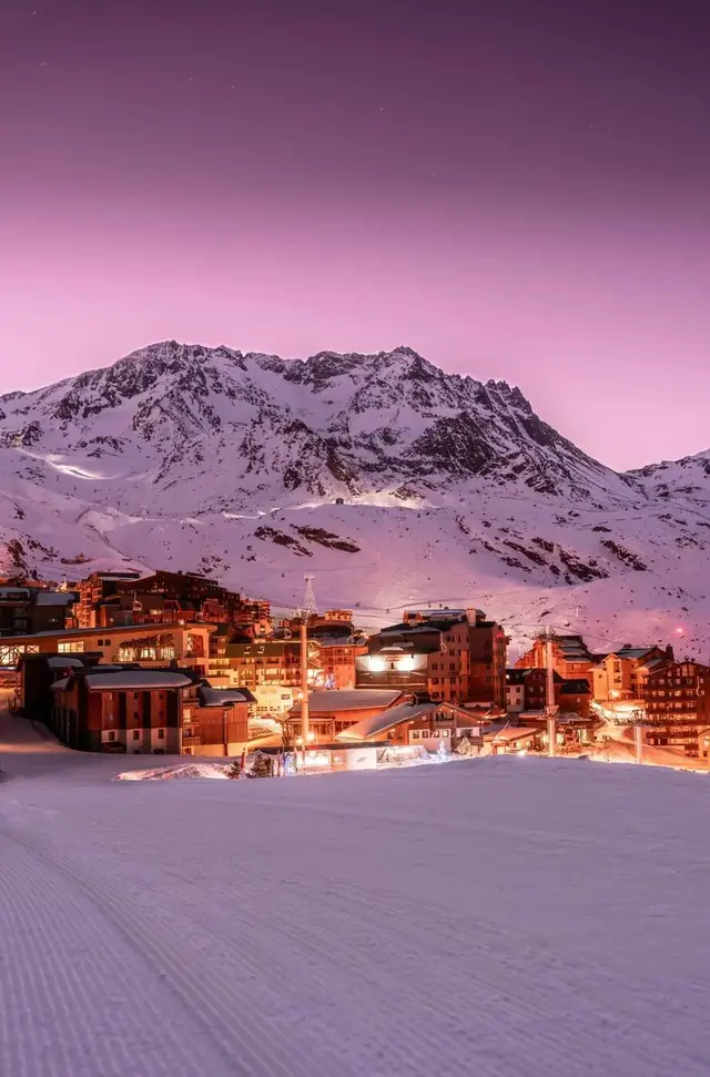 La station de Val Thorens illuminée au crépuscule, au pied de ses sommets enneigés
